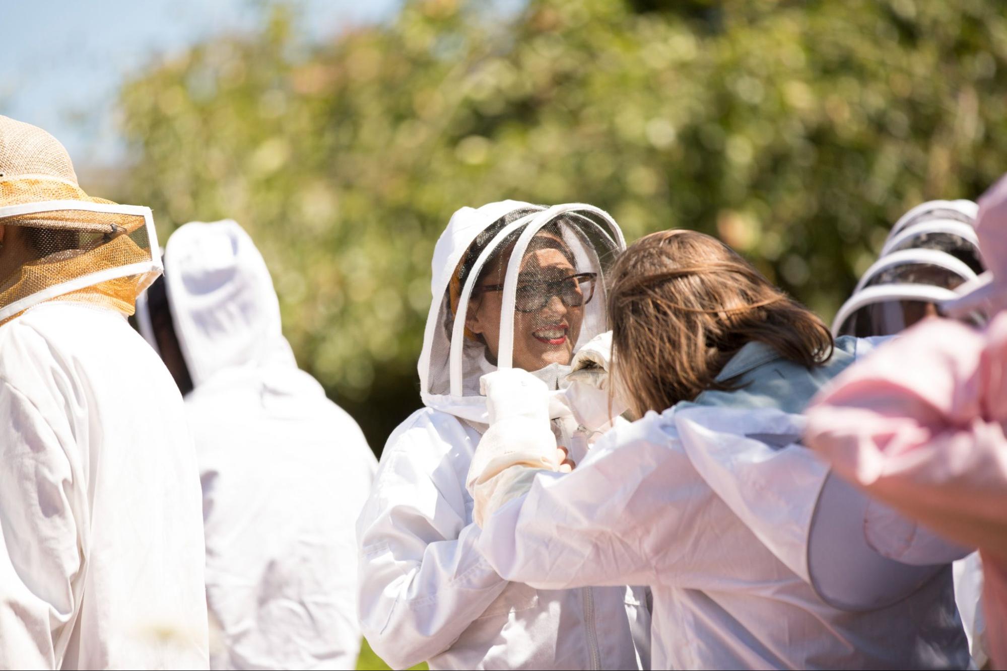 A guest is fitted with beekeepers mask at an Intro to Beekeeping event