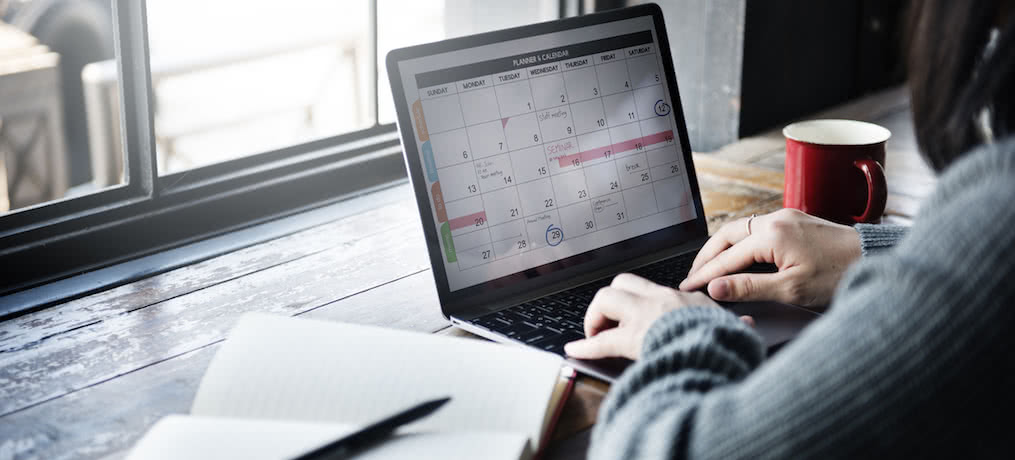 Woman looks at calendar on her laptop.