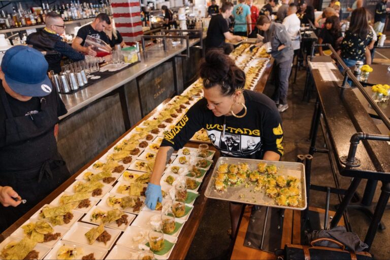 Picture of catering employees preparing food in plates for the attendees.