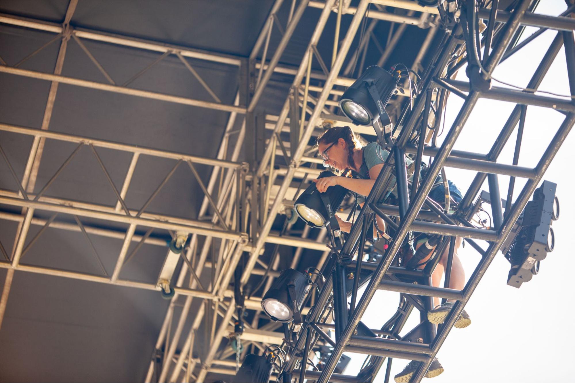 Woman adjusting the stage lights in preparation for an event.