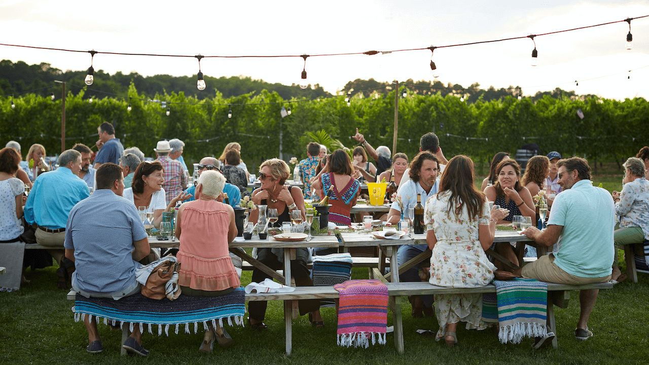 People sitting in tables at a beautiful garden and chatting.