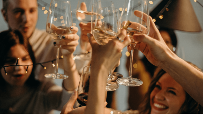 Friends clink wine glasses together at party