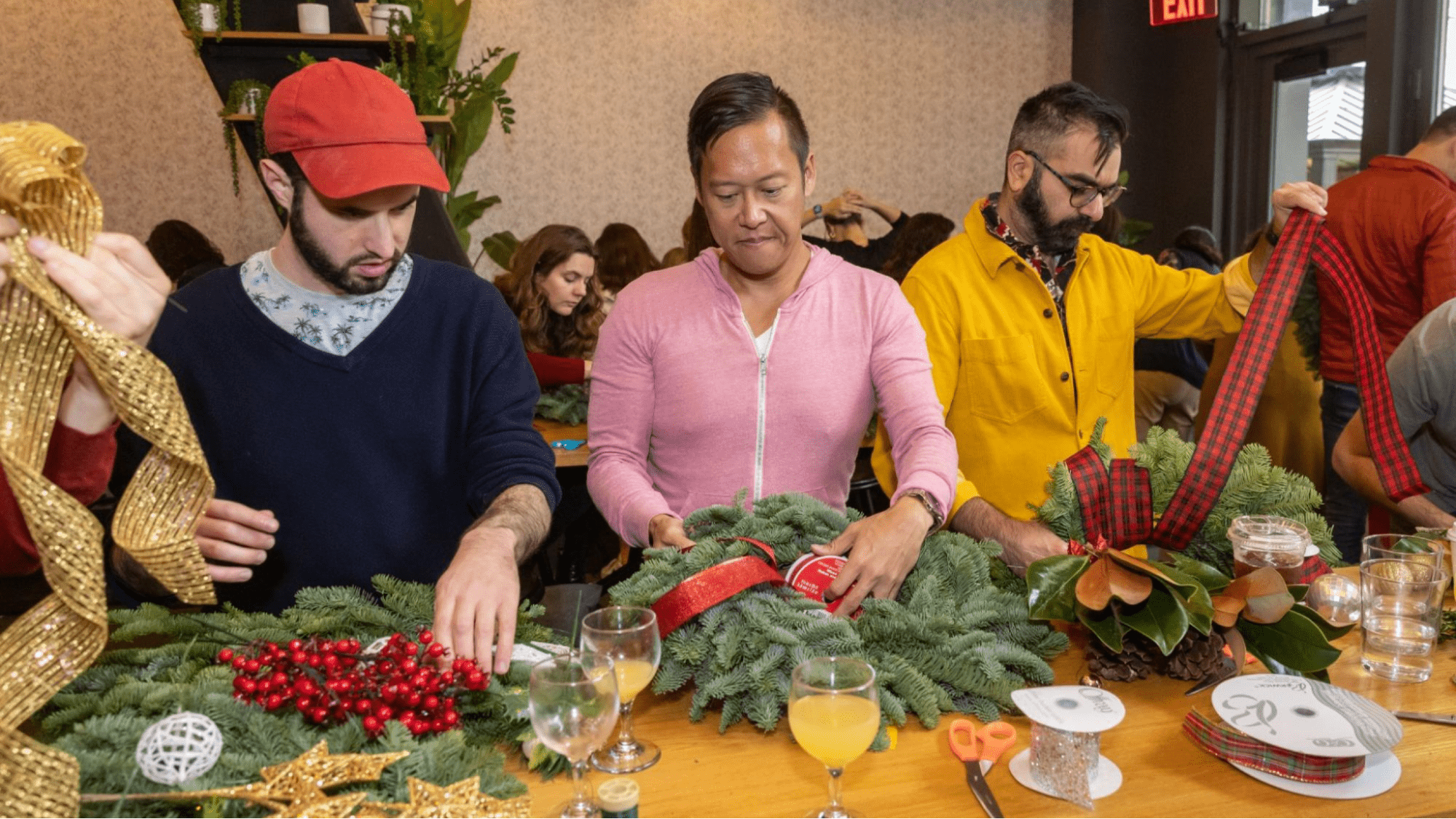 Wreath making event. Three men make wreaths at a table.
