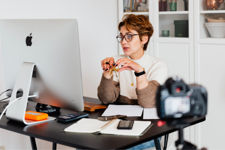 Woman sitting at a desk facing a computer appearing to engage in virtual conference call.