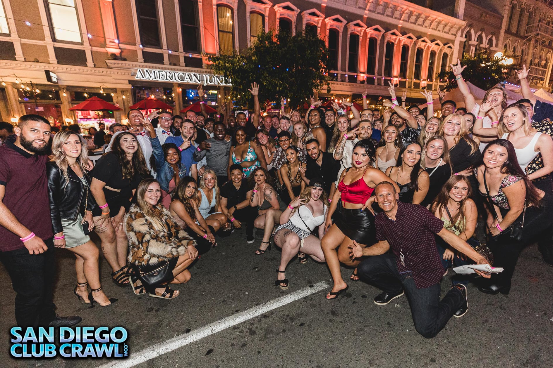 A group of event-goers on San Diego Club Crawl pose for a photo on the street.