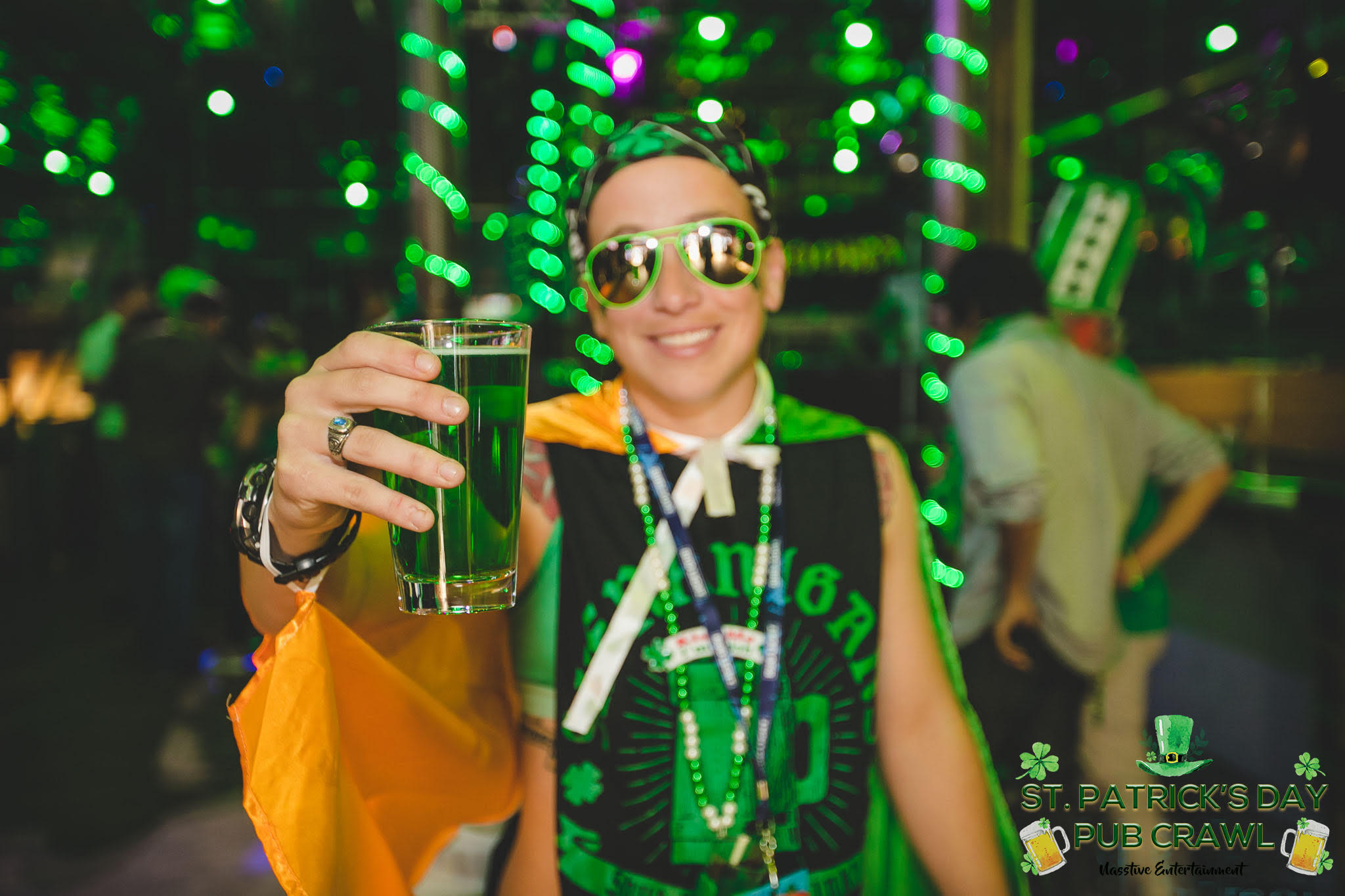 A man dressed in green holding a pint on St Patrick's Day bar crawl.